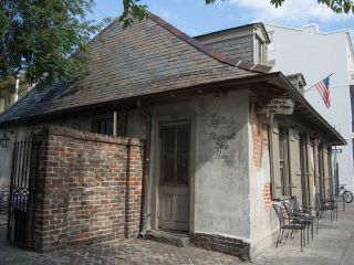 A Close Up Of A Brick Building With Lafitte's Blacksmith Shop In The Background