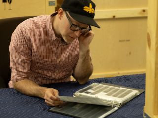 A Man Sitting At A Table Using A Laptop
